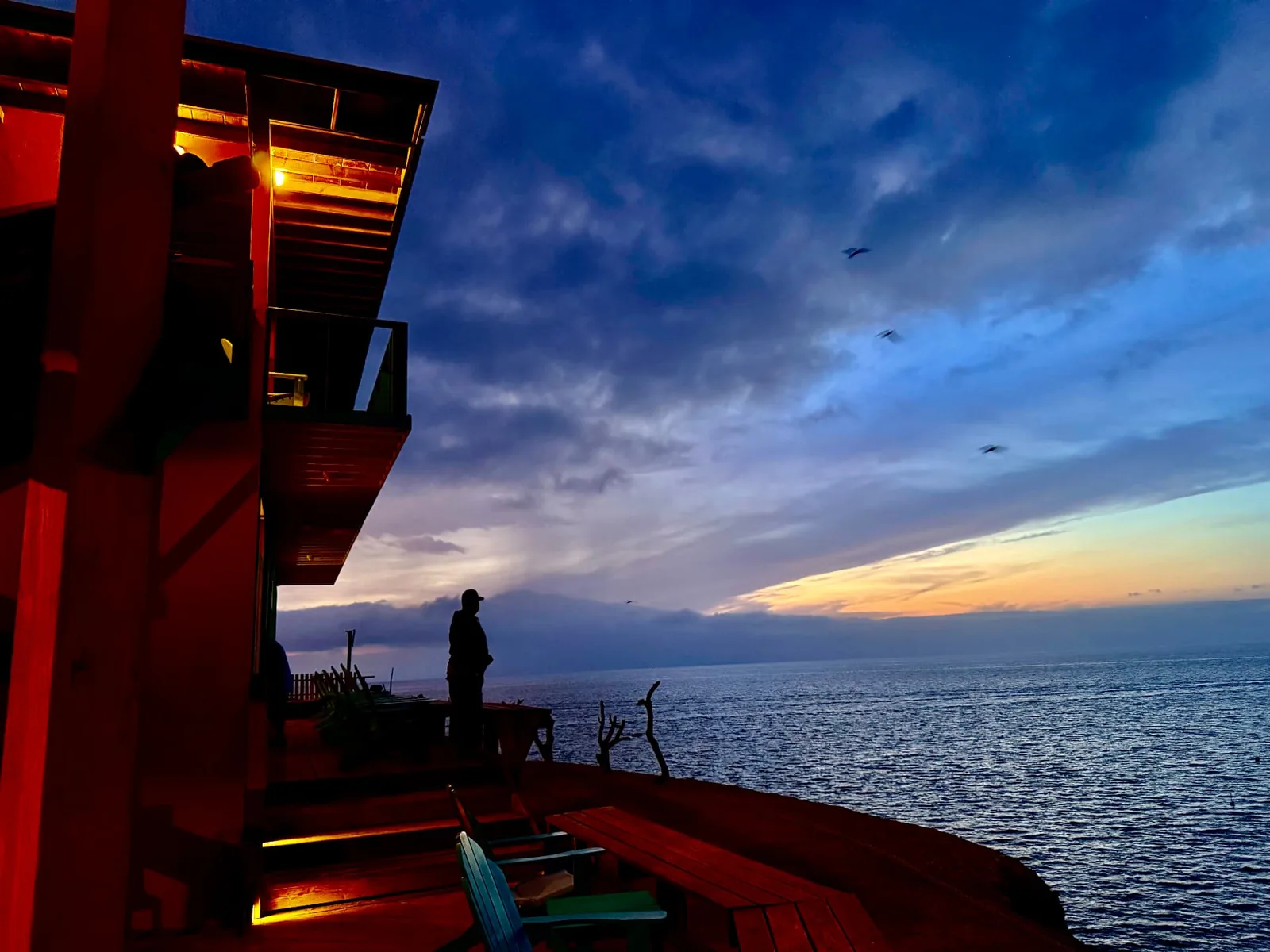 Sunset over the Pacific with the warm lights of the lodge deck at Isla Cedros