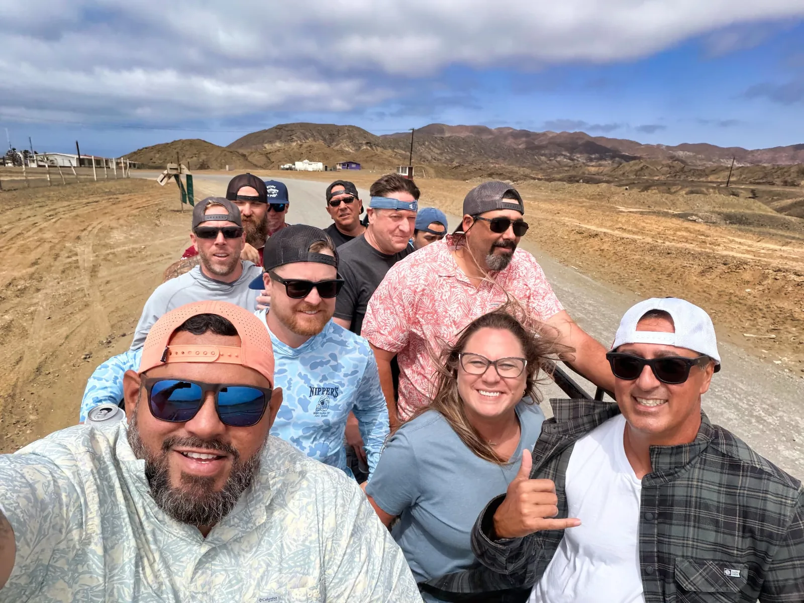 Anglers ride together in an open vehicle on a dirt road through the arid hills of Isla Cedros