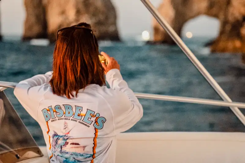 Angler in a Bisbee's tournament shirt watching the fleet from a boat near the Cabo San Lucas arch