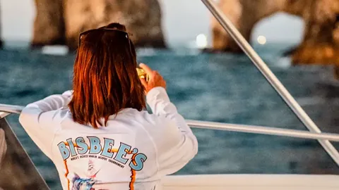 Angler in a Bisbee's tournament shirt watching the fleet from a boat near the Cabo San Lucas arch