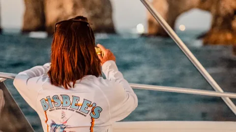 Angler in a Bisbee's tournament shirt watching the fleet from a boat near the Cabo San Lucas arch