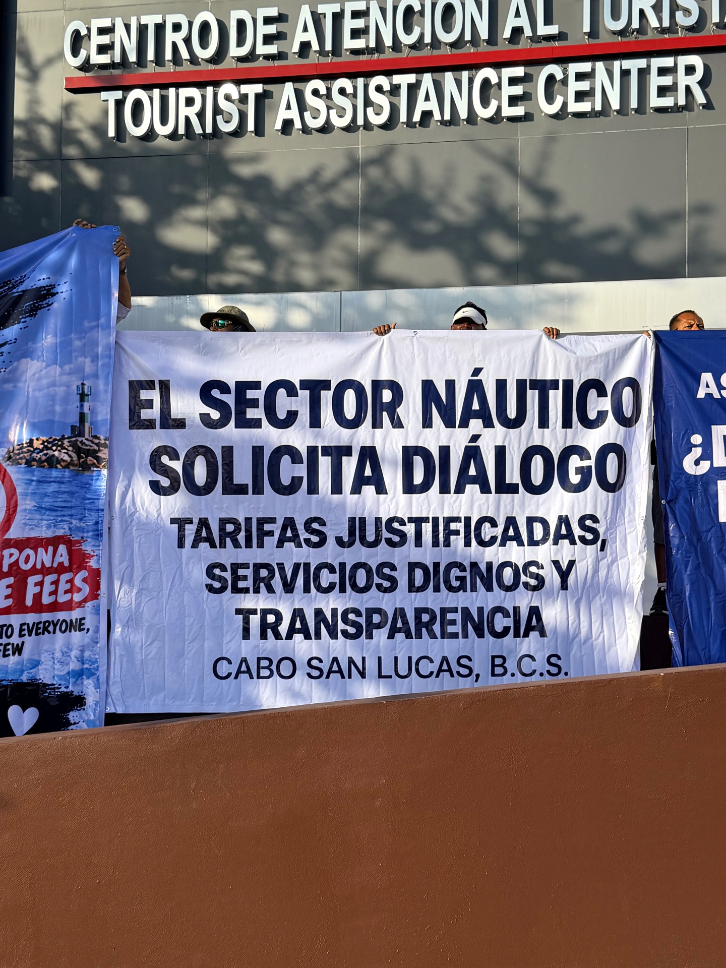 Demonstrators hold a Spanish banner requesting dialogue, justified tariffs, adequate services and transparency outside Cabo San Lucas’s Tourist Assistance Center.