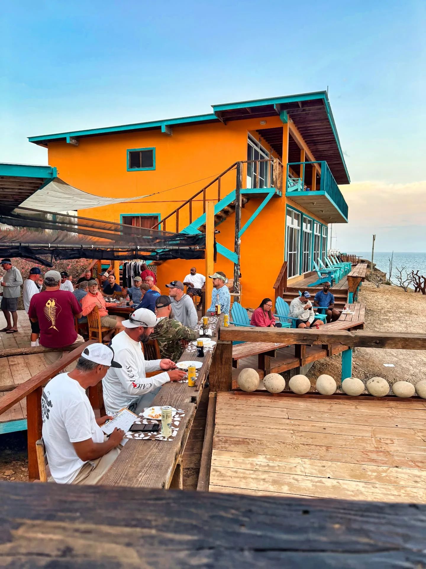 Anglers gather on the wooden oceanfront deck of the lodge at Isla Cedros in late-afternoon light