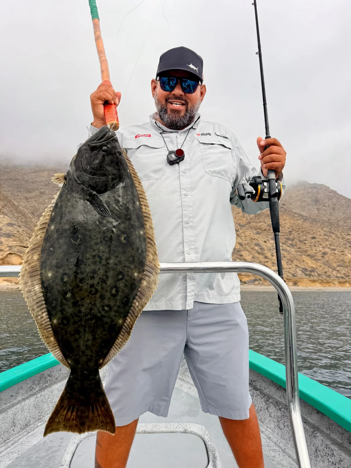 An angler holds a halibut aboard a panga at Isla Cedros.