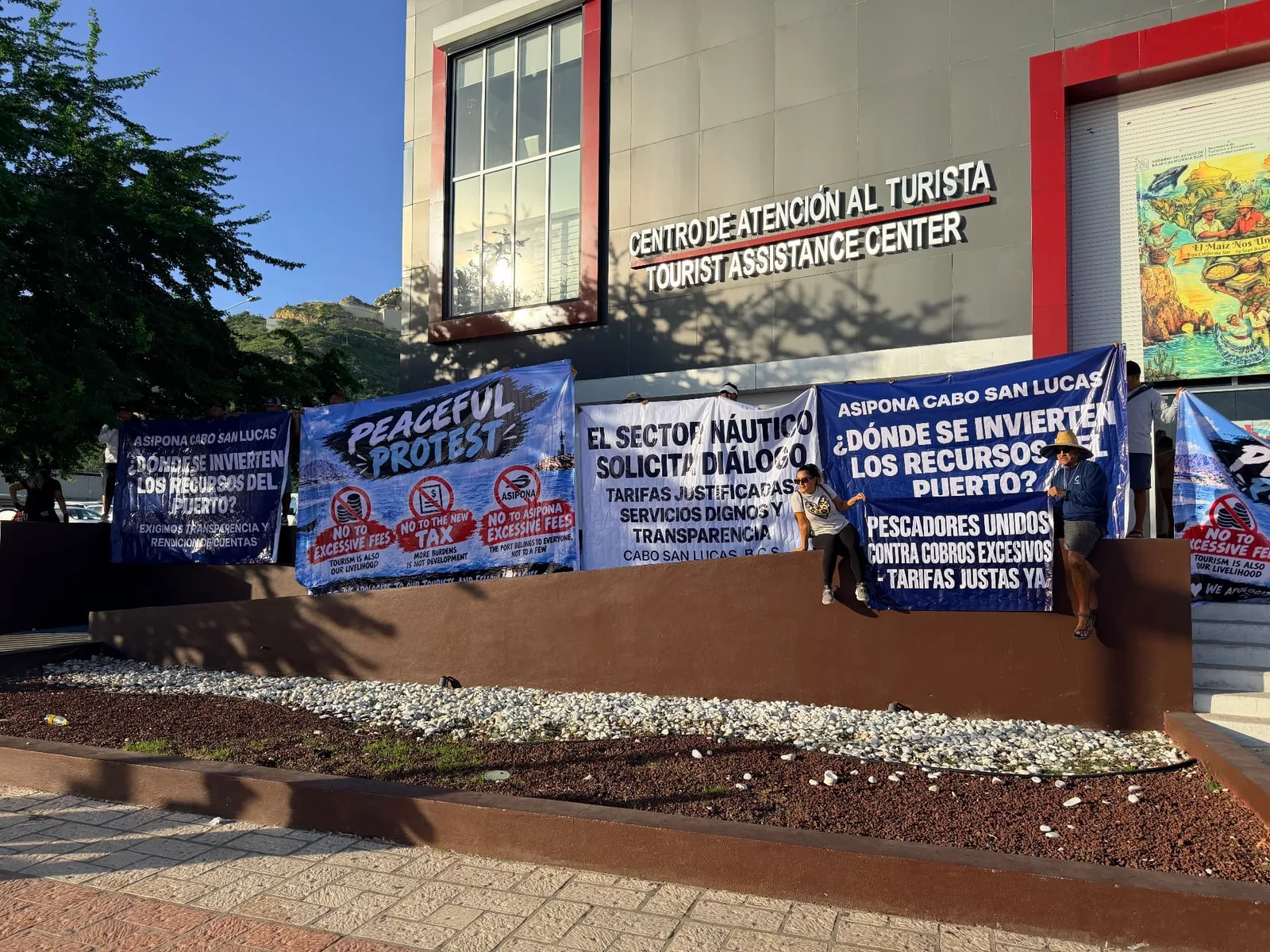 Peaceful protest banners against the new ASIPONA port fees outside the tourist assistance center in Cabo San Lucas